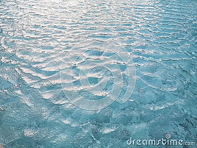 Waving pattern of vivid turquoise blue water in the swimming pool above stone tiles with soft light of reflection of the sunshine Stock Photo