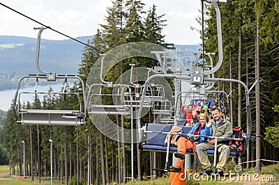 Waving young people sitting on chairlift Stock Photo