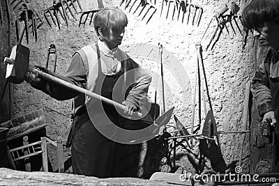 Wax figure of ancient blacksmith hit iron, black and white image Editorial Stock Photo