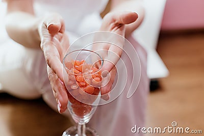 Wax in the form of granules for depilation of pink color is filled in a champagne glass. Waxing La depilation in hands holding a Stock Photo