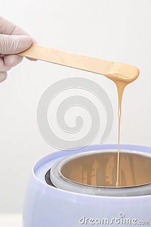 Wax heater with hot wax on wooden spatula Stock Photo