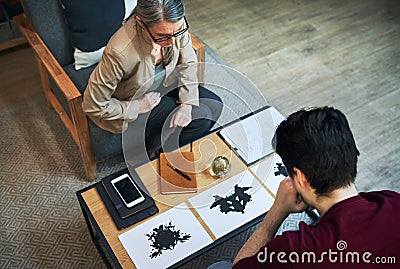 A way to scan the subconscious. Shot of a mature psychologist conducting an inkblot test with her patient during a Stock Photo