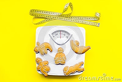 Ways for lose weight. Sport. Cookies in shape of yoga asans near scale and measuring tape on bright yellow background Stock Photo