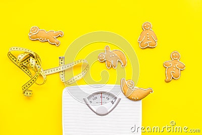 Ways for lose weight. Sport. Cookies in shape of yoga asans near scale and measuring tape on bright yellow background Stock Photo