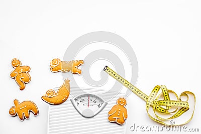 Ways for lose weight. Sport. Cookies in shape of yoga asans near scale and measuring tape on white background top view Stock Photo