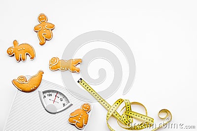 Ways for lose weight. Sport. Cookies in shape of yoga asans near scale and measuring tape on white background top view Stock Photo