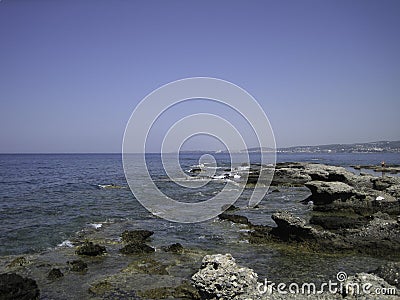Weak waves gently wash the stones lying on the shallow bottom of the sea rocky shore in good weather Stock Photo