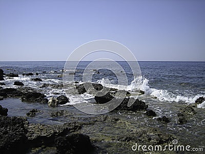 Weak waves gently wash the stones lying on the shallow bottom of the sea rocky shore in good weather Stock Photo