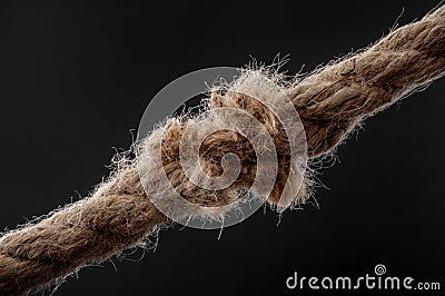 Weakness, vulnerability and single point of failure concept with worn rope string breaking under physical stress pulling on it Stock Photo