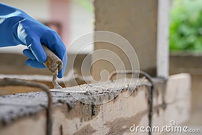 Wear glove hand of industrial bricklayer hold aluminium brick trowel installing mortar wall on construction site Stock Photo