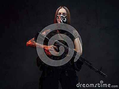 Weared with mask female mercenary holding rifle Stock Photo