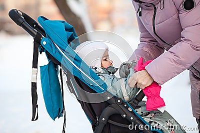 Wearin pink mittens on children hands while walking with stroller in winter cold time, close-up view Stock Photo