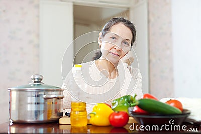 Weariness mature woman at kitchen Stock Photo