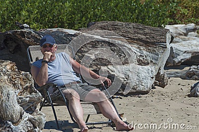 Man lounges in a folding chaise on the beach at Siletz Bay Park, Lincoln City, Oregon Stock Photo