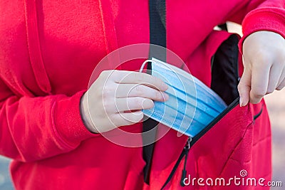 Wearing medical mask in public places concept. Cropped close up photo of young girl taking medical mask to use Stock Photo