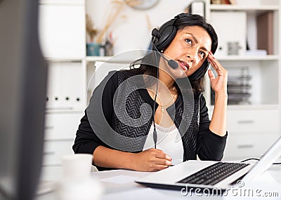 Weary woman with microphone headset at work in office Stock Photo