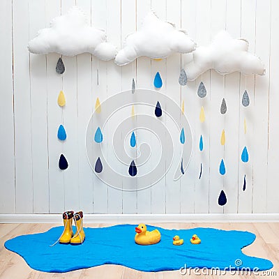 Weather symbols. Handmade room decoration clouds with rain drops, puddle, child yellow rubber boots and ducks Stock Photo