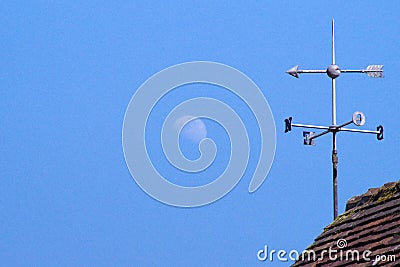 A weather vane on the roof pointing at the full moon. Stock Photo