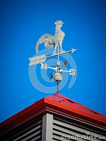 Weather vane on red roof Stock Photo