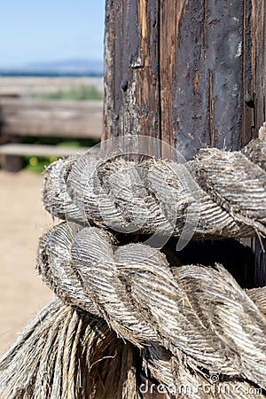 Weatherd rope tied around wood post Stock Photo