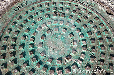 Weathered copper stained manhole cover Stock Photo