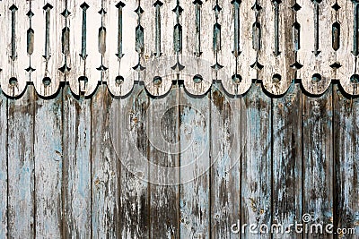 Weathered painted blue peeling wooden fence and rounded carved wooden decor on top. Stock Photo