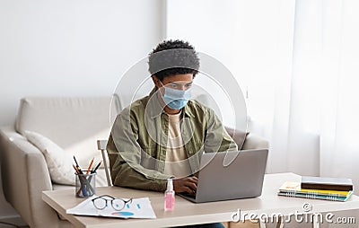 Web based learning during covid-19 pandemic. Teenage male student in mask attending online class on laptop at home Stock Photo
