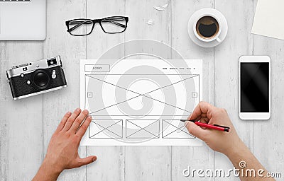 Web designer draw layout of website on paper. Top view of work desk with computer, phone, camera Stock Photo