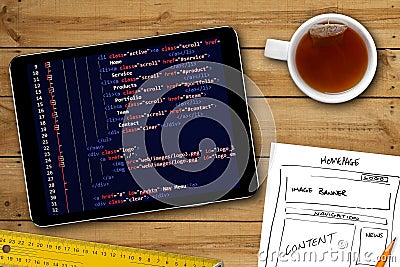 Website wireframe sketch and programming code on digital tablet Stock Photo