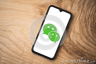 Wechat application on smartphone. Wooden background. Top angle shot Editorial Stock Photo