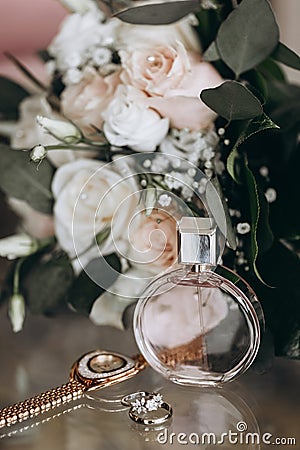 Wedding accessories of the bride in the form of a bouquet of roses, wedding rings with precious stones and perfume Stock Photo