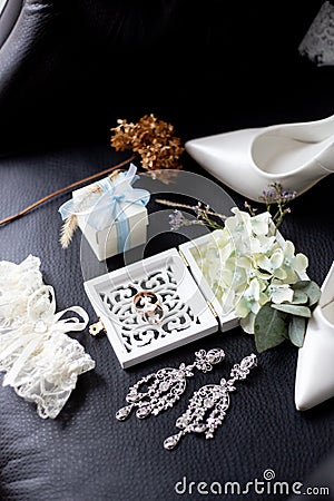 Wedding rings in a decorative box with flowers, earrings, women`s shoes, a garter of the bride, a small gift Stock Photo