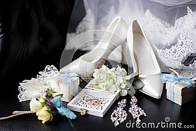 Wedding rings in a decorative box with flowers, earrings, women`s shoes, a garter of the bride, a small gift Stock Photo