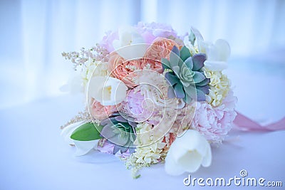 Wedding bouquet featuring trendy succulents, peachy peonies, white tulips, and ivory roses, embellished with ribbons Stock Photo