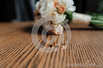Wedding bouquet of fresh flowers, a pair of gold rings close-up. Wedding details Stock Photo