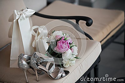 Wedding. Bouquet of pink, white flowers and greenery is in a chair against next to the bride`s shoes Stock Photo