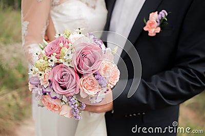 Wedding couple hugging, the bride holding a bouquet of flowers in her hand, the groom embracing Stock Photo