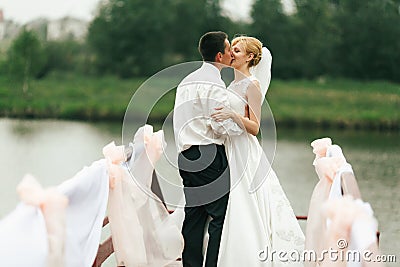 A wedding couple kisses tenderly standing on a bridge decorated Stock Photo