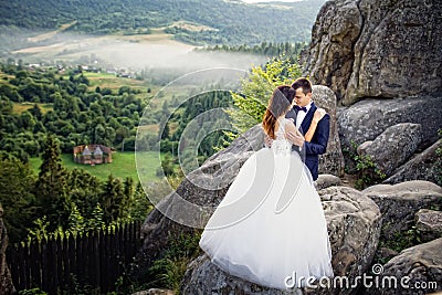 Wedding couple standing in the mountains against the sky. Cute r Stock Photo