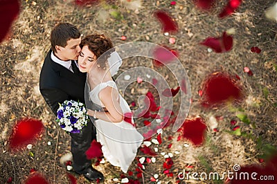 Wedding couple under a rain of rose petals. Stock Photo