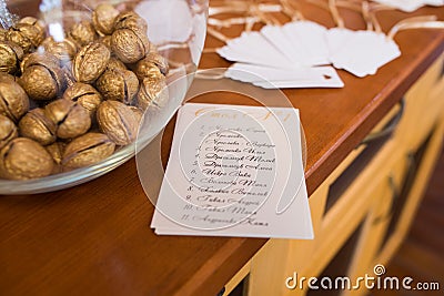 Golden walnut in a glass round vase and a guest seating list. Wedding decor Stock Photo