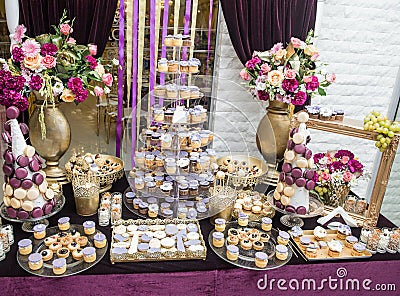 Wedding decoration with multicolored roses in vase, pastel colored cupcakes, meringues, muffins and macarons Stock Photo