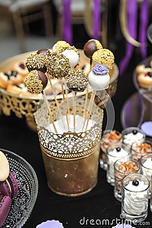 Wedding decoration with various lollipops in golden support, cupcakes, meringues, muffins and macaroons. Elegant and luxurious Stock Photo