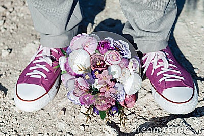 Wedding details in the form of purple sneakers and a purple wedding bouquet. Stock Photo