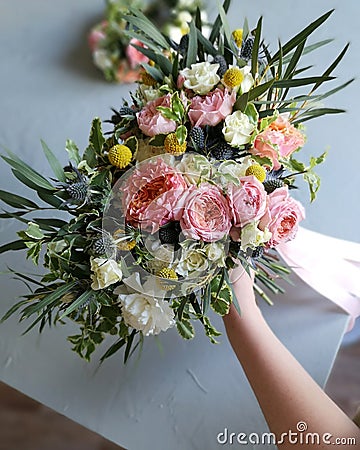 Wedding disheveled flower bouquet with long ribbons and female hands on florist table in workshop. Pink and white flowers. Top vie Stock Photo