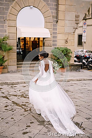 Wedding in Florence, Italy. African-American bride in a white dress with a long veil and a bouquet in her hands. Stock Photo