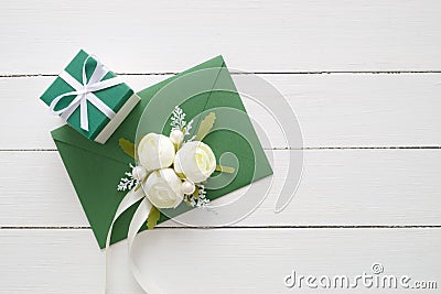 Wedding invitation card or Valentines Day letter in green envelope decorated with white rose flowers and gift box. Stock Photo