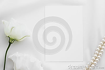 Wedding invitation, white rose flowers and pearls on silk fabric as bridal flatlay background, blank paper greeting card Stock Photo