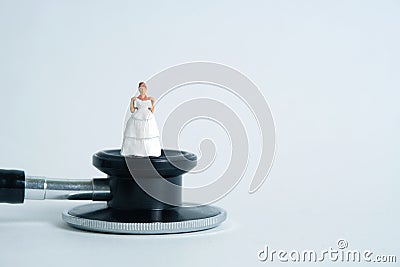 Wedding marriage and couple medical check-up concept miniature people toy photography. Bride and groom with stethoscope isolated Stock Photo