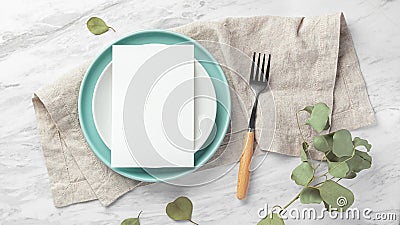 Wedding menu card on plate with fork on linen napkin on marble table with green leaves Stock Photo